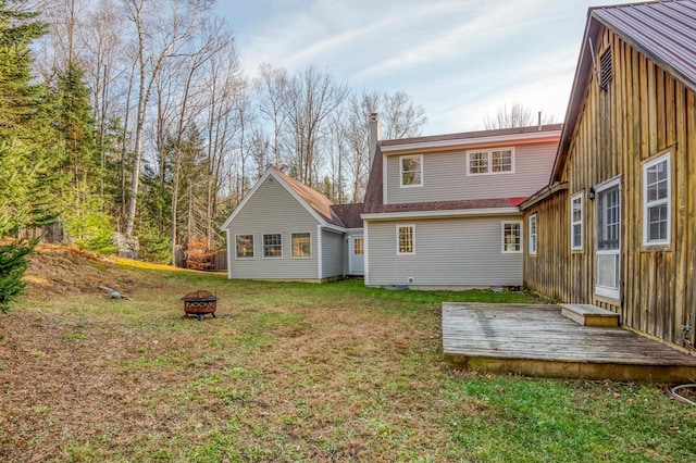 rear view of property with a deck, an outdoor fire pit, and a lawn