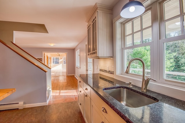 kitchen featuring sink, baseboard heating, dark stone counters, and tile patterned flooring