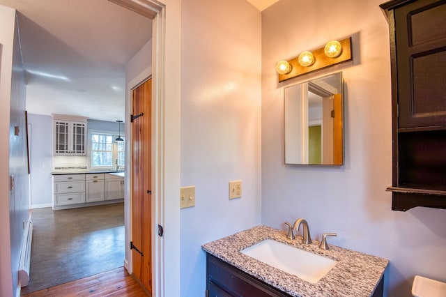 bathroom featuring a baseboard heating unit, sink, and hardwood / wood-style flooring