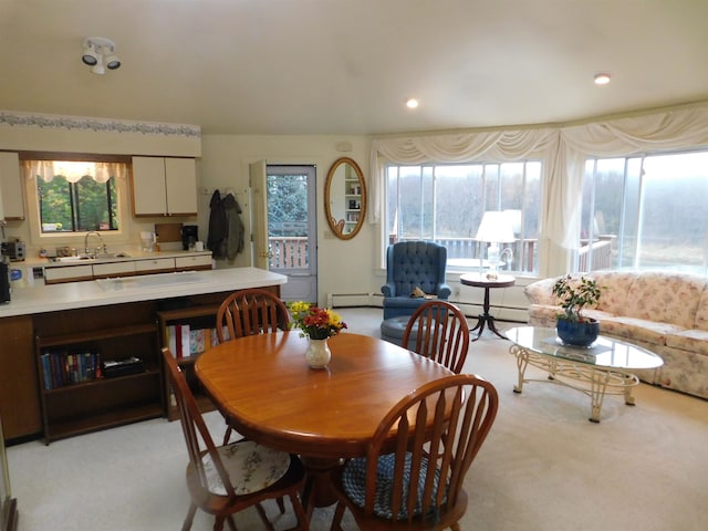 carpeted dining area featuring a wealth of natural light, sink, and a baseboard heating unit