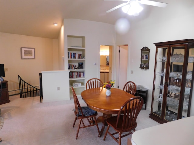 dining area with built in features, light colored carpet, and ceiling fan