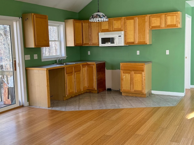 kitchen featuring decorative light fixtures, light hardwood / wood-style floors, sink, and lofted ceiling