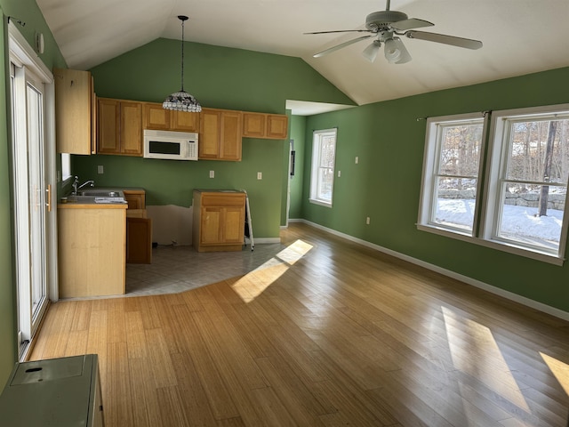 kitchen featuring lofted ceiling, hanging light fixtures, ceiling fan with notable chandelier, light hardwood / wood-style flooring, and sink