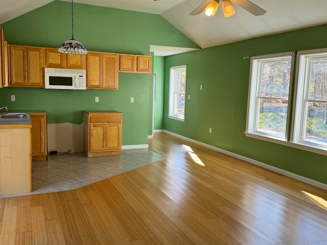 kitchen featuring light wood-type flooring, decorative light fixtures, sink, vaulted ceiling, and ceiling fan