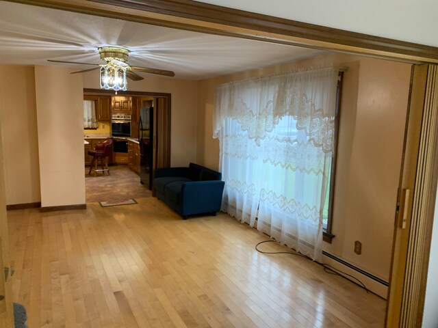 spare room with ceiling fan, baseboard heating, and light hardwood / wood-style floors