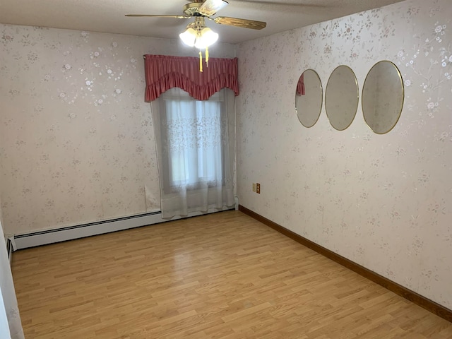 empty room featuring ceiling fan, a textured ceiling, light hardwood / wood-style floors, and a baseboard heating unit