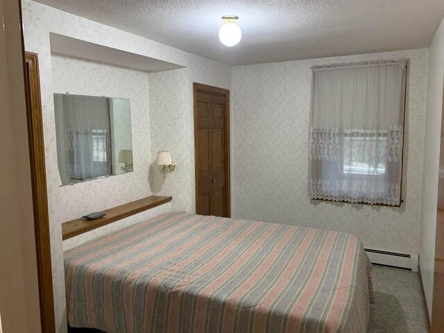 bedroom with a baseboard radiator and a textured ceiling