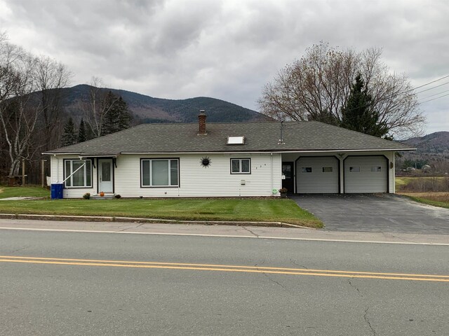 ranch-style house with a mountain view, a garage, and a front yard
