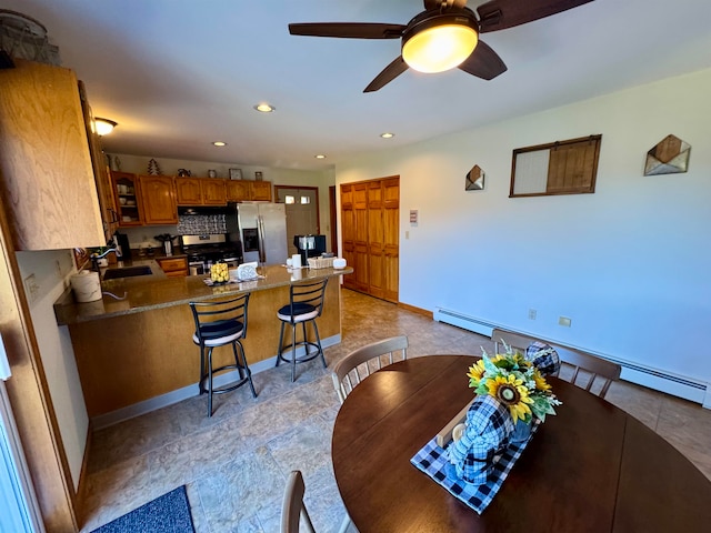 kitchen with appliances with stainless steel finishes, sink, a breakfast bar, kitchen peninsula, and baseboard heating