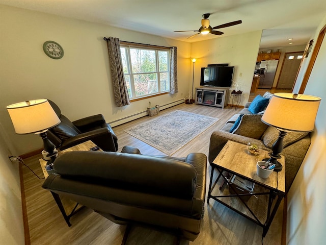 living room featuring hardwood / wood-style flooring, ceiling fan, and a baseboard heating unit