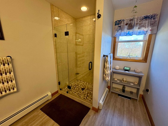 bathroom featuring an enclosed shower, hardwood / wood-style flooring, and a baseboard heating unit