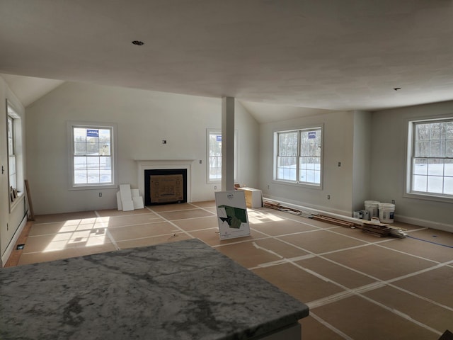 unfurnished living room featuring lofted ceiling, light tile patterned floors, and a healthy amount of sunlight