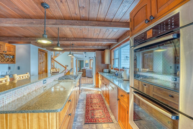 kitchen featuring stainless steel appliances, a kitchen island, beam ceiling, hanging light fixtures, and sink