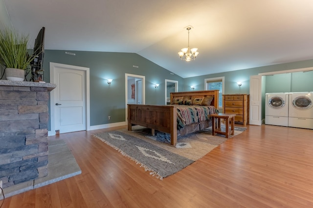 bedroom with hardwood / wood-style floors, a notable chandelier, separate washer and dryer, and vaulted ceiling