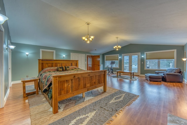 bedroom with french doors, light wood-type flooring, lofted ceiling, and an inviting chandelier