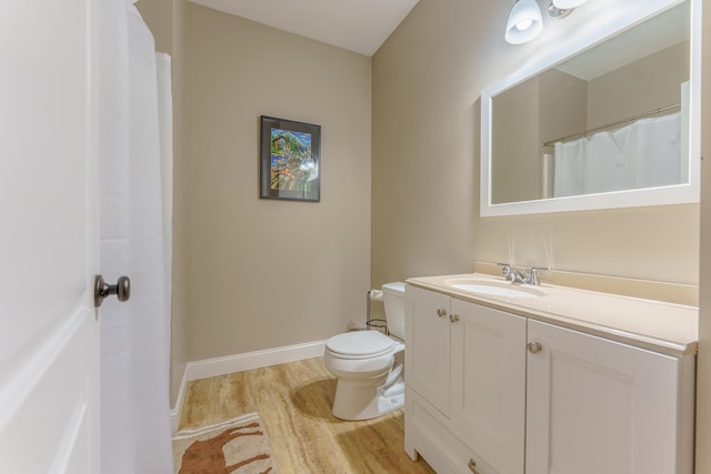 bathroom featuring wood-type flooring, toilet, and vanity