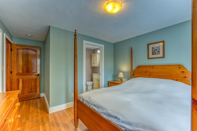 bedroom featuring connected bathroom and light hardwood / wood-style floors