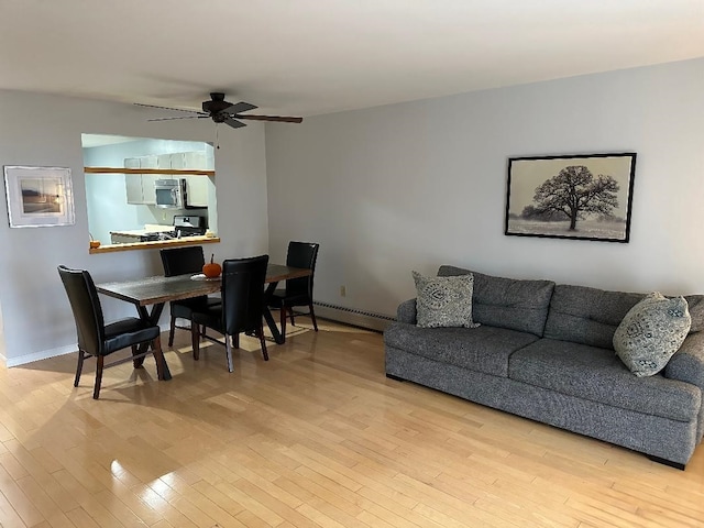 living room featuring a baseboard heating unit, light hardwood / wood-style floors, and ceiling fan