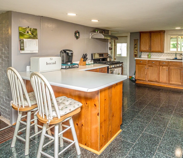 kitchen featuring gas stove, a wealth of natural light, kitchen peninsula, and a breakfast bar area