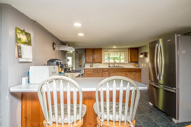 kitchen with kitchen peninsula, appliances with stainless steel finishes, sink, and tasteful backsplash