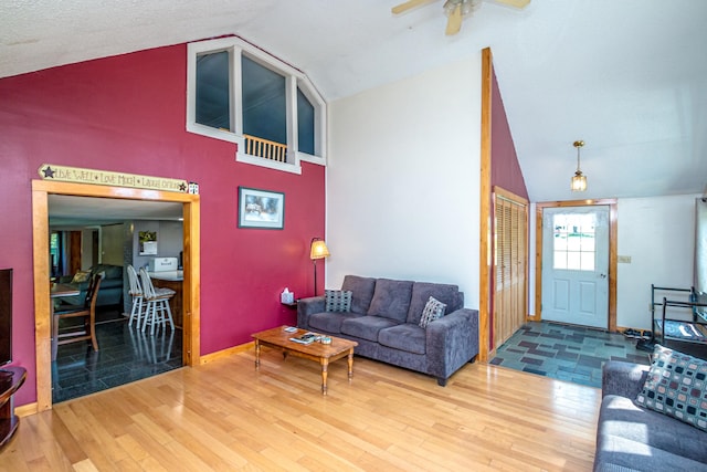 living room featuring lofted ceiling, wood-type flooring, ceiling fan, and a textured ceiling