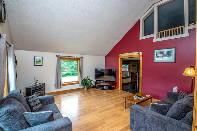 living room featuring wood-type flooring, vaulted ceiling, a wood stove, and a textured ceiling