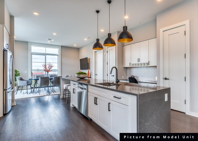 kitchen with stainless steel appliances, white cabinets, sink, and a kitchen island with sink