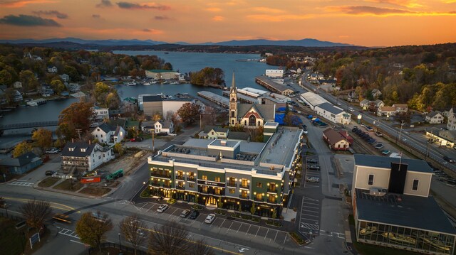 aerial view at dusk featuring a water and mountain view