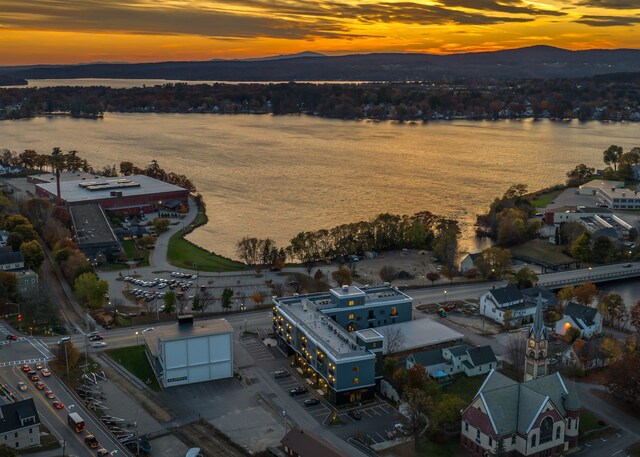 aerial view at dusk featuring a water and mountain view