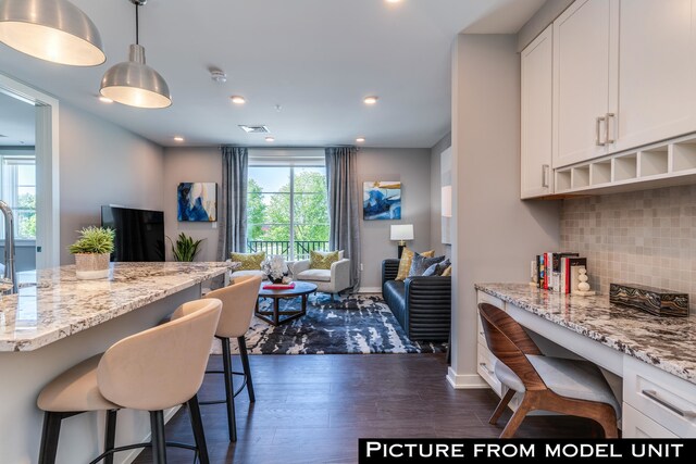 kitchen featuring white cabinetry, a healthy amount of sunlight, dark hardwood / wood-style floors, and a breakfast bar