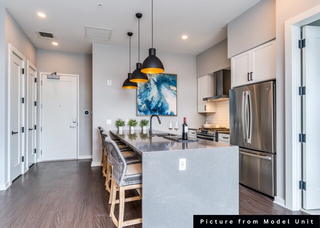 kitchen with stainless steel appliances, dark hardwood / wood-style floors, white cabinets, wall chimney range hood, and pendant lighting