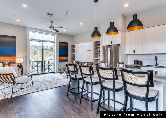 kitchen with stainless steel appliances, white cabinetry, backsplash, sink, and dark wood-type flooring