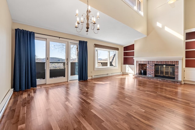 unfurnished living room with a brick fireplace, hardwood / wood-style flooring, a chandelier, and a baseboard radiator