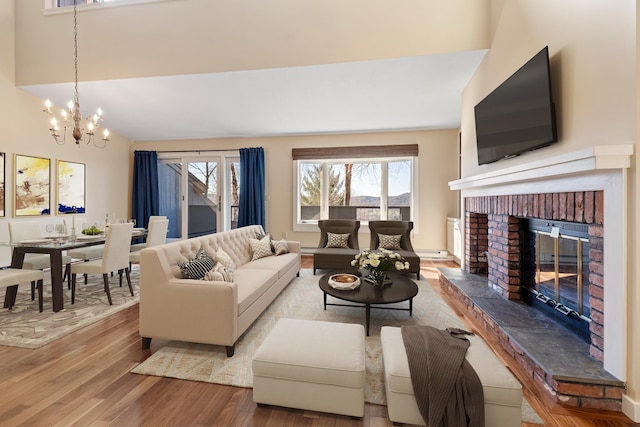 living room with hardwood / wood-style floors, a fireplace, vaulted ceiling, and a notable chandelier