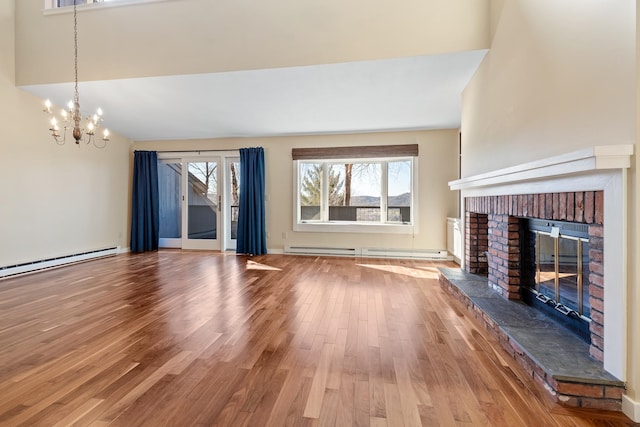 unfurnished living room with a fireplace, hardwood / wood-style flooring, an inviting chandelier, and a baseboard heating unit