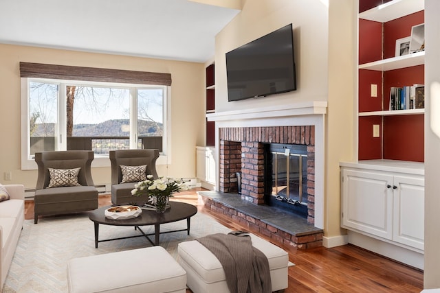 living room with hardwood / wood-style floors, a baseboard heating unit, and a brick fireplace