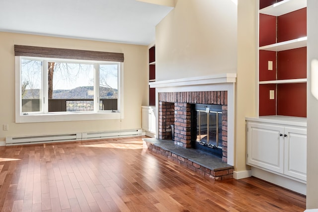 unfurnished living room featuring a fireplace, a baseboard radiator, and hardwood / wood-style floors