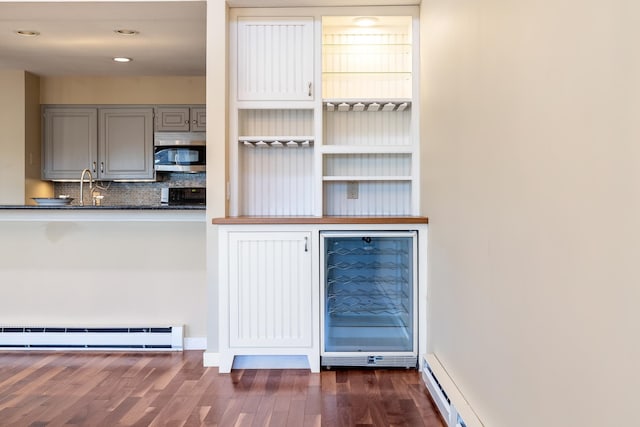 bar with gray cabinets, sink, decorative backsplash, dark wood-type flooring, and baseboard heating