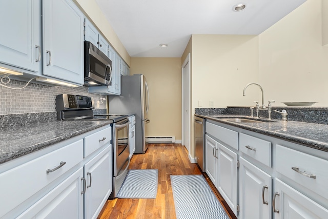 kitchen with a baseboard radiator, stainless steel appliances, light hardwood / wood-style floors, sink, and white cabinetry