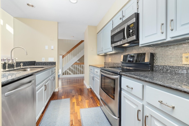 kitchen featuring stainless steel appliances, dark stone counters, sink, and dark hardwood / wood-style floors