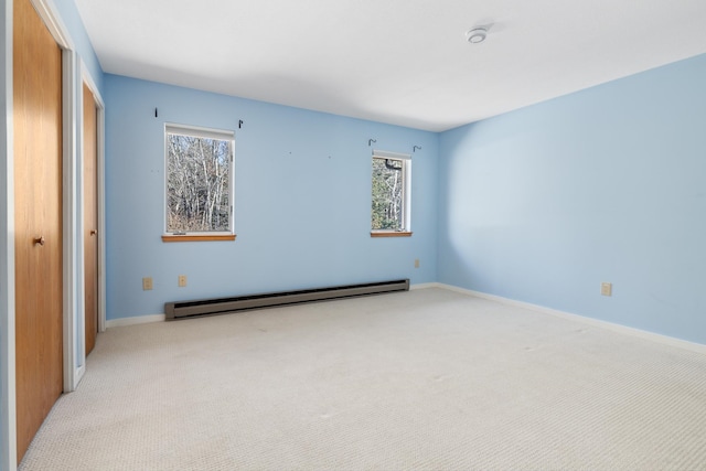 carpeted spare room with a baseboard heating unit