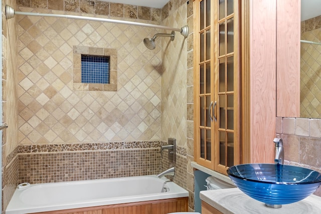 full bathroom featuring tiled shower / bath combo, tile walls, sink, and toilet