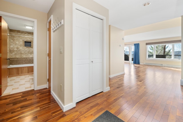 hallway with dark wood-type flooring and a baseboard heating unit