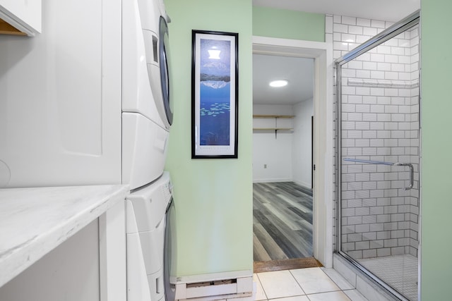 bathroom with hardwood / wood-style flooring, stacked washer and dryer, and a shower with shower door