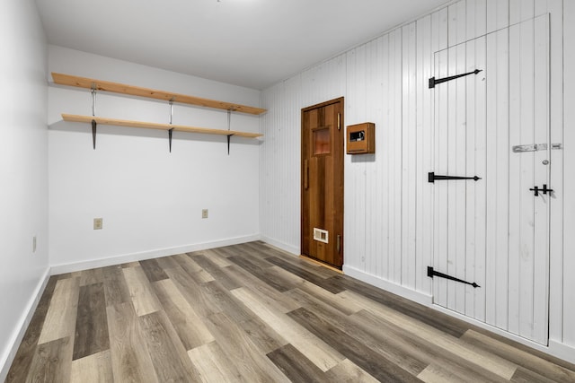 unfurnished room featuring light hardwood / wood-style floors and wooden walls