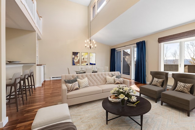 living room with high vaulted ceiling, a baseboard radiator, hardwood / wood-style flooring, and an inviting chandelier