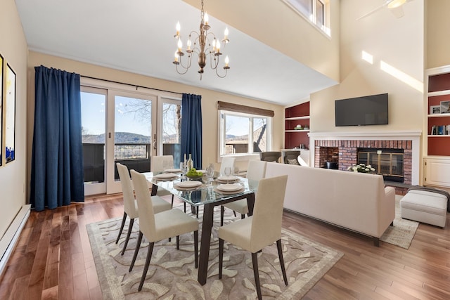 dining room featuring a brick fireplace, hardwood / wood-style floors, plenty of natural light, and baseboard heating