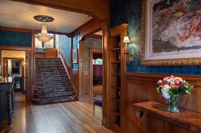 stairway with wood-type flooring, a textured ceiling, crown molding, and decorative columns