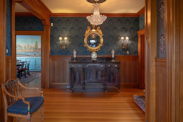 bar with ornate columns, wood-type flooring, crown molding, and an inviting chandelier