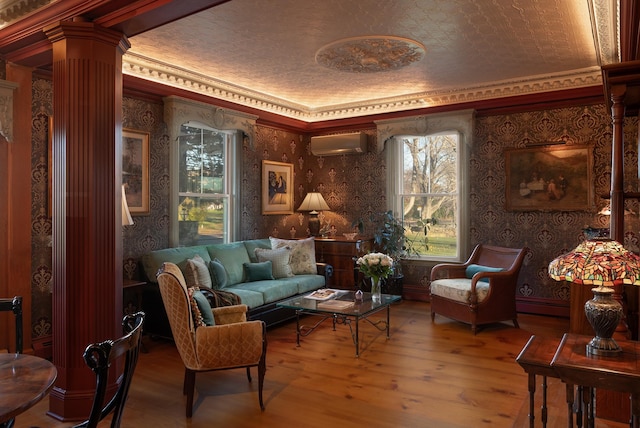 living area featuring ornamental molding, a wall mounted AC, hardwood / wood-style flooring, a baseboard heating unit, and decorative columns